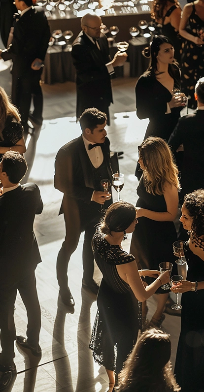 Mensen in formele kleding mengen zich onder elkaar op een chique cocktailparty. Warme sfeerverlichting en een elegante inrichting zorgen voor een verfijnde en levendige sfeer.